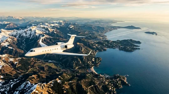 Vue aérienne d'un jet privé survolant un paysage européen avec des montagnes et un littoral méditerranéen